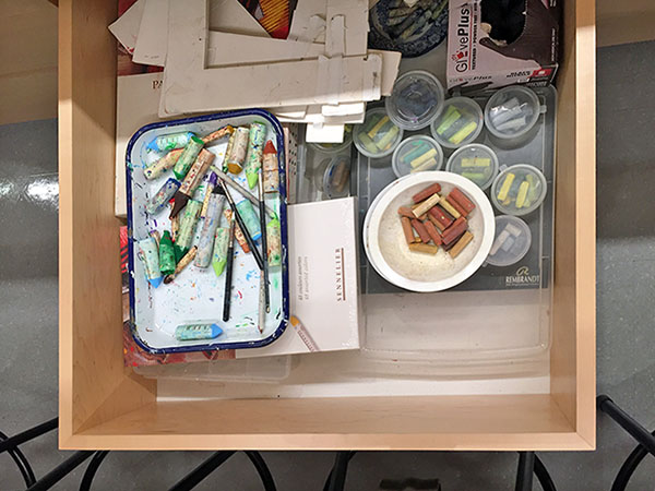Art pastels are stored for art class in art storage drawer in school art studio.