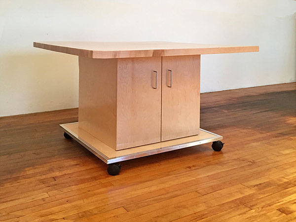 Artist work table has deep adjustable shelving behind doors for storing art, artist tools, and art supply materials.