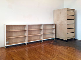 Open shelving has adjustable leveling feet and adjustable shelves. They stand next to the 65" tall bank of mobile art studio storage drawers on wheels.