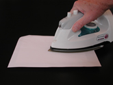 Quickly move the hot iron over the cover sheet to adhere the art to the mounting panel.