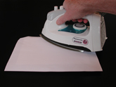 Move the hot iron over the cover sheet to heat the panel so that the art will be mounted to the panel.